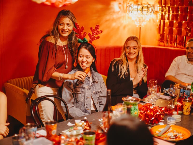 Woman holding microphone up to another woman at Christmas party